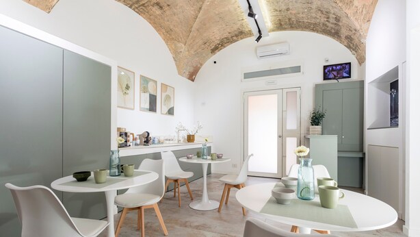 A modern kitchen with white cabinetry, a round dining table, and white chairs. - Neg Naumachia Rooms - Triple Room 3 (Catania)