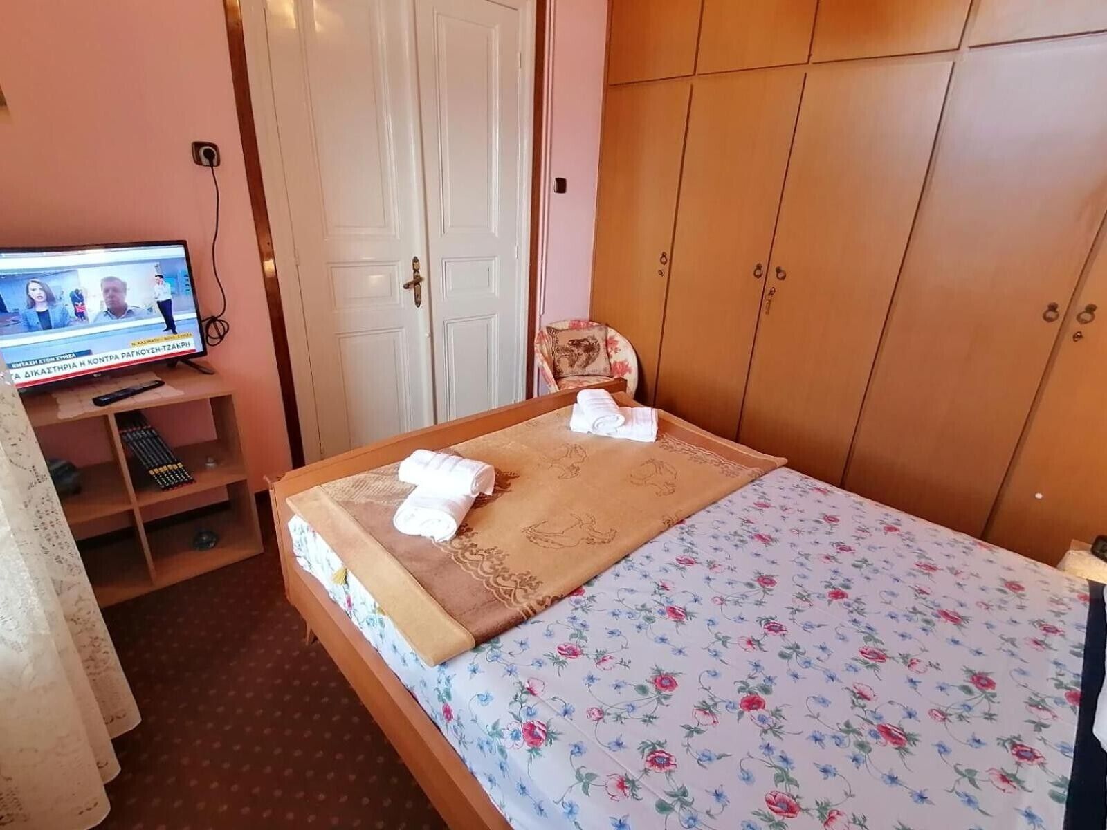 A hotel room with a bed, a television, a wardrobe, and a chair.
