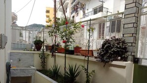 Um pequeno pátio com plantas em vasos, um espelho d'água e piso de azulejos.