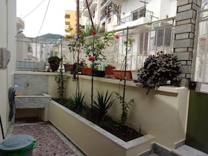 A small courtyard with potted plants, a water feature, and a tiled floor.