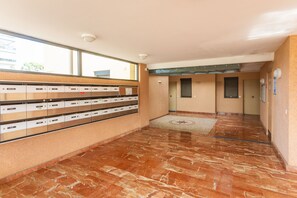 Un hall d’entrée avec un sol en marbre, une rangée de casiers et une porte au fond.