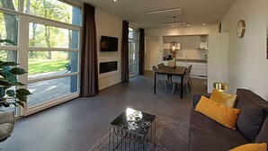 A modern living room with a sofa, coffee table, and a dining area with a table and chairs. - Holiday Home in Otterlo With Terrace (Otterlo)