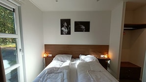 A hotel room with two beds, a wooden headboard, two bedside lamps, and two framed pictures on the wall. - Holiday Home in Otterlo With Terrace (Otterlo)