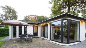 Een moderne woning met een terras, een eethoek en een glazen ruimte.
