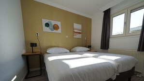 Een hotelkamer met een groot bed, twee nachtkastjes en kunstwerken aan de wanden.
