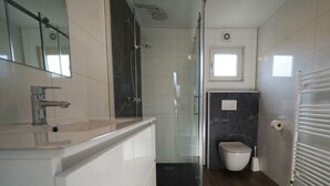 Een badkamer met een douche, toilet en wastafel.