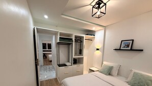 Ein Schlafzimmer mit Bett, begehbarer Kleiderschrank, Nachttisch und einer Wandablage mit einem Bild.