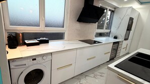 Eine kleine Küche mit Waschmaschine, Herd und Spüle.