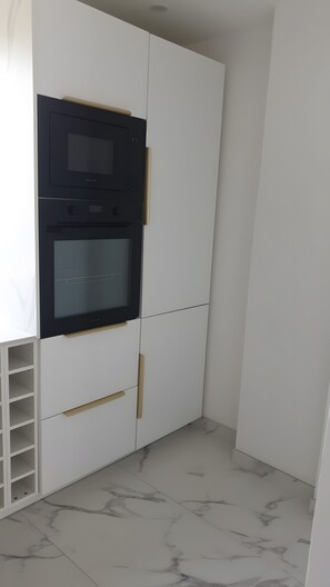 Ein weißer Kleiderschrank mit integriertem schwarzen Gerät, möglicherweise einer Mikrowelle.