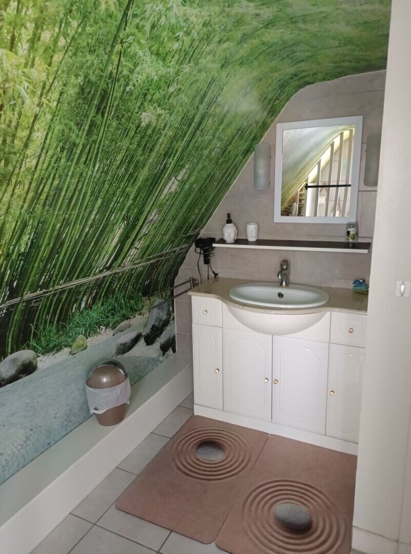 A bathroom with a green wall, a sink, cabinets, and a mirror.