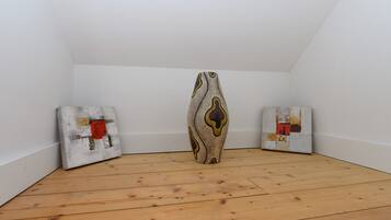 Una habitación con piso de madera, paredes blancas y tres obras de arte en las paredes.