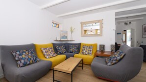 Ein modernes Wohnzimmer mit einem grauen Sofa, einem gelben Sofa und einem grauen Sessel, einem Holztisch als Couchtisch und einem kleinen Holztisch.
