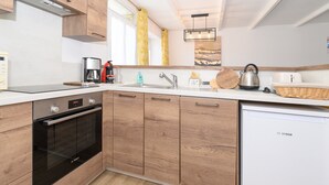 Eine moderne Küche mit Holzausstattung, einem Geschirrspüler von Bosch, einer Kaffeemaschine und einem Wasserkocher.