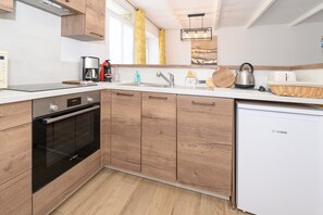 Eine moderne Küche mit Holzausstattung, einem Geschirrspüler von Bosch, einer Kaffeemaschine und einem Wasserkocher.