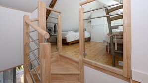 Ein Schlafzimmer mit einer Holztreppe, einem Bett und einem großen Fenster.