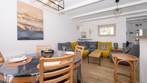 Ein modernes Wohnzimmer mit Essbereich, ausgestattet mit einer Sofagarnitur, einem Holztisch und einem Esstisch mit Stühlen.
