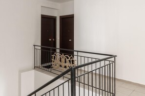 Un interior limpio y moderno con una escalera pulida, puertas de madera oscura y barandilla de metal.