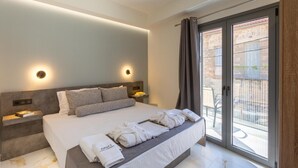 Ein modernes Hotelzimmer mit einem großen Bett, Nachttischen und einer Schiebeglastür zu einem Außenbereich.