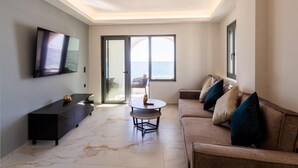 Ein modernes Wohnzimmer mit Fernseher, einer Couch, einem Couchtisch und Meerblick durch große Fenster.
