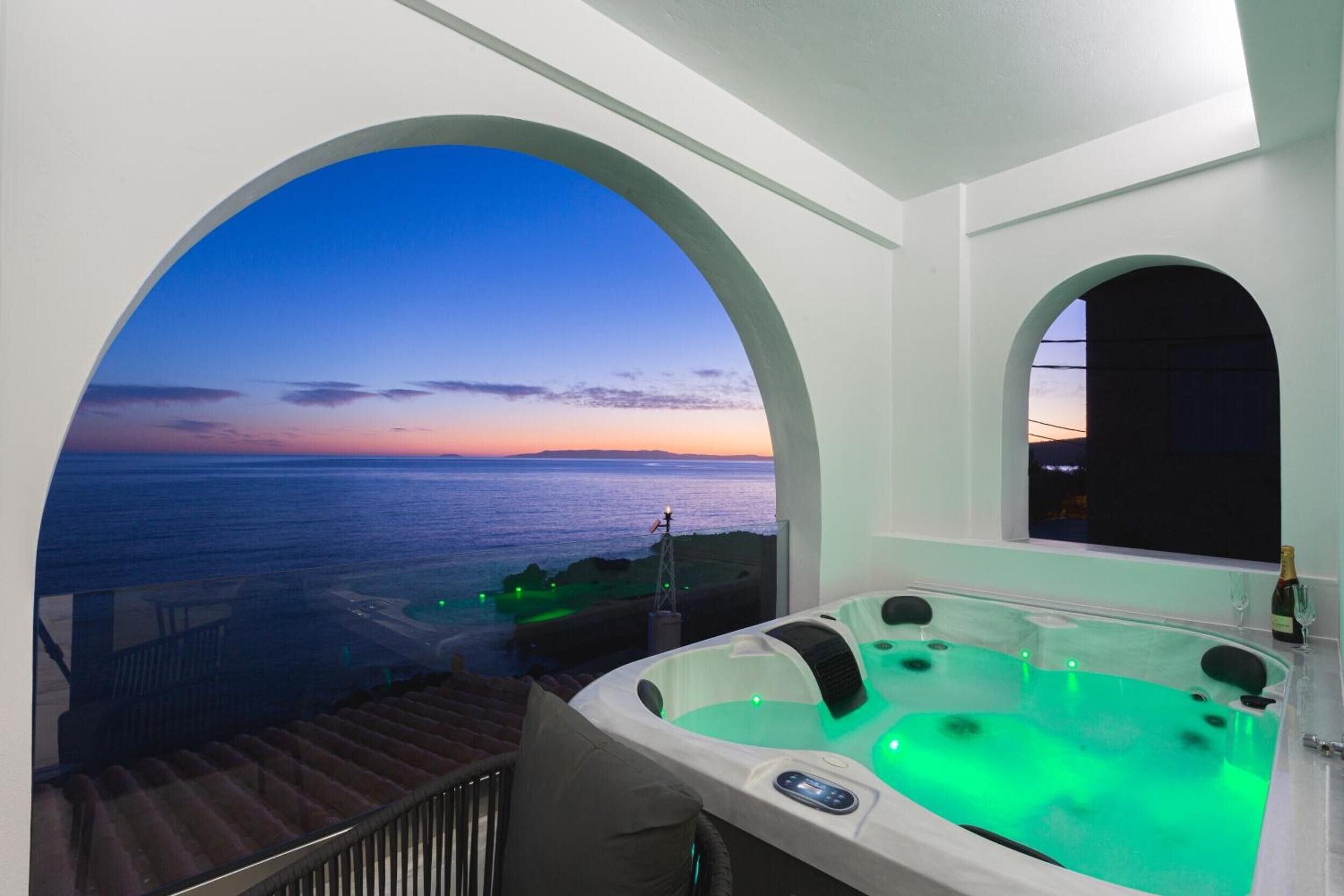 A hot tub with a sunset view through an arched window.