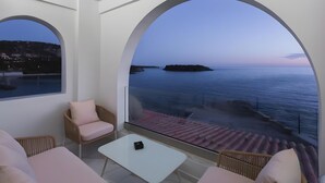Ein Balkon mit Meerblick, einem weißen Tisch und Korbstühlen.