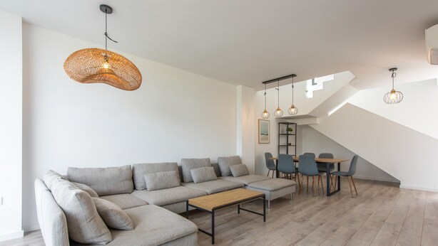 Ein modernes Wohnzimmer mit einer Eckcouch, einem Holztisch und einem Essbereich mit Stühlen und Tisch.