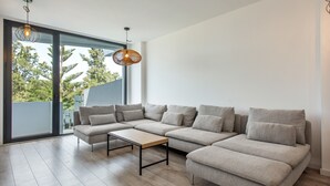 Ein modernes Wohnzimmer mit einer Eckcouch, einem Couchtisch und einer Pendelleuchte.