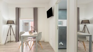 Una habitación moderna con una mesa de comedor, sillas, un televisor de pantalla plana y una lámpara.