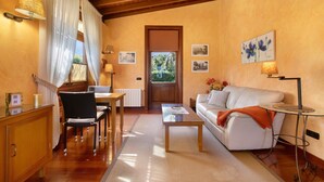 Una sala de estar acogedora con techo de madera, un sofá blanco, una mesa de centro y un comedor con sillas y una mesa.