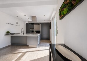 Cozinha moderna com ilha central, eletrodomésticos embutidos e uma grande janela.