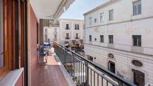A balcony with a view of a street, a building with a balcony, and a door.