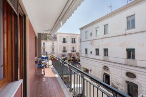 Un balcó amb vistes a un carrer, un edifici amb balcó i una porta.