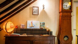 A room with a wooden desk, a globe, books, a painting, a clock, and a framed picture on the wall.