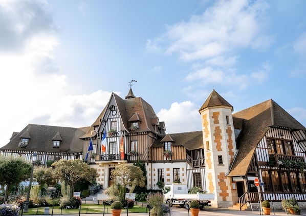 Un bâtiment traditionnel à colombages, doté d’un toit à forte pente, d’une tour centrale et d’un mât pour drapeau.