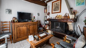A cozy living room with a fireplace, wooden furniture, a television, and various decorative items.