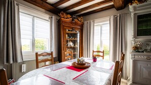 A dining room with a table set for four, wooden chairs, a cabinet with glass doors, and a window with curtains.