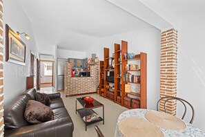 Un salon avec un canapé en cuir, une table basse, une bibliothèque et un mur en briques.
