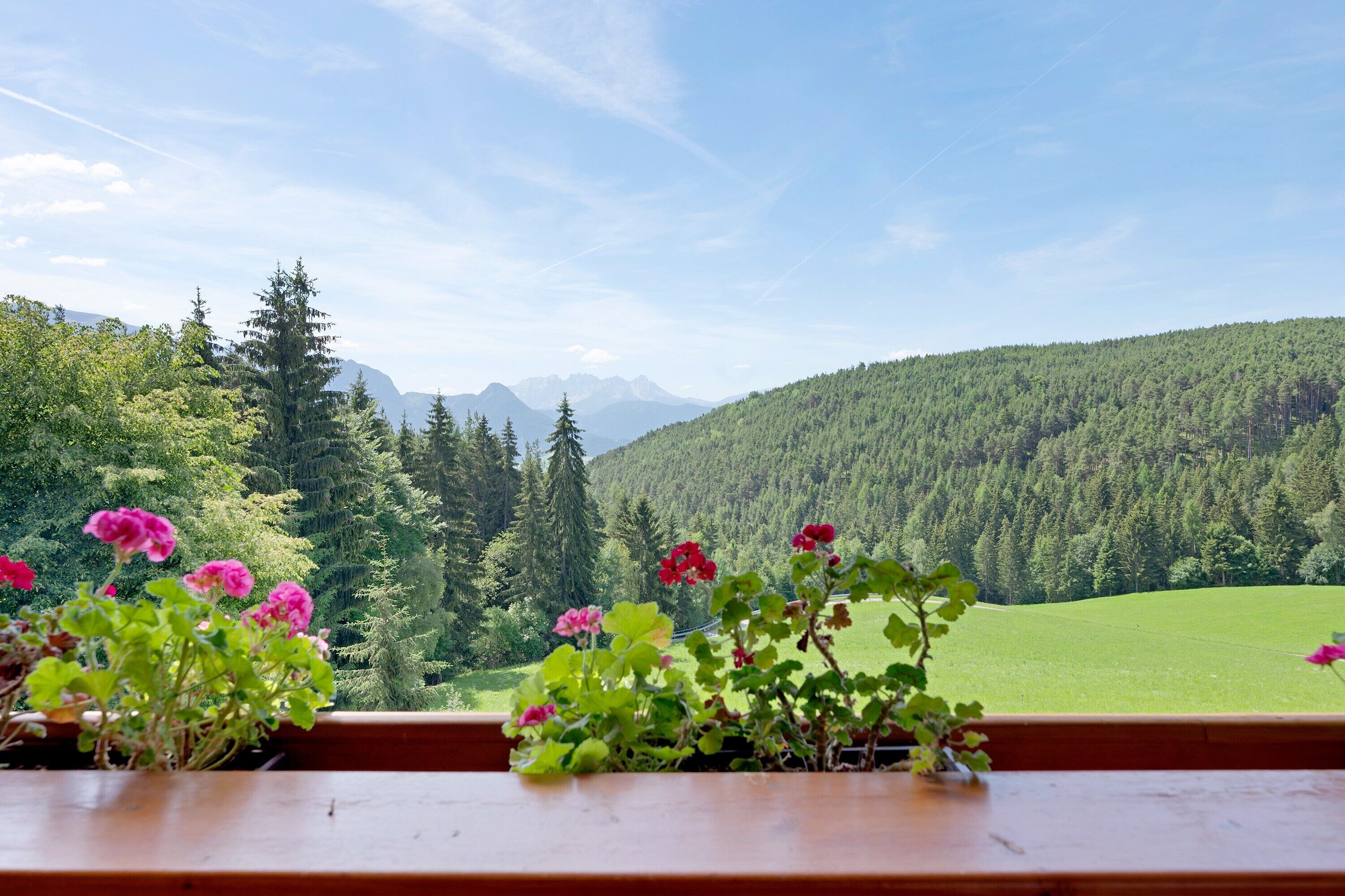 Une vue d’un paysage montagneux, avec une table en bois au premier plan.