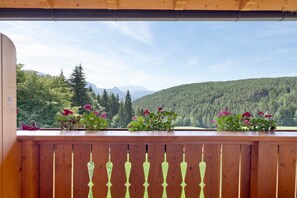 Un balcón de madera con vistas a una cadena montañosa boscosa.