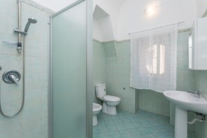 Ein Badezimmer mit Dusche, Toilette, Waschbecken und einer Duschkabine aus Glas.
