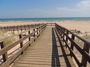 Een houten looppad dat naar een strand leidt, met een helder uitzicht op de oceaan.