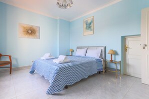 Une chambre à coucher avec un lit, deux tables de chevet, une chaise et une porte.