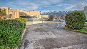 A parking lot with cars, a building with 'DA VINCI' signage, and a mountain backdrop. - Luxurious Romantic Suite with Jacuzzi, Wi-Fi, and Air Conditioning (Saint-Martin-d'Hères)