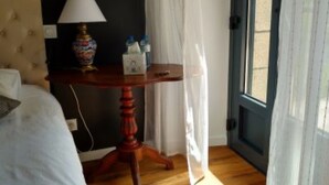 Ett sovrum med en säng, ett nattduksbord med en lampa, ett fönster med gardiner och en dörr.