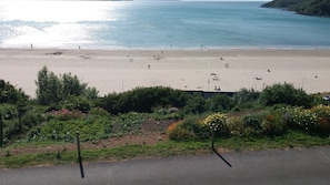 Una playa con gente, una carretera al frente y vegetación.