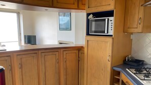 Una cocina con gabinetes de madera, microondas, estufa a gas y una ventana.