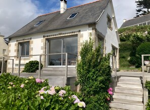 Et moderne hus med to etager, stenvæg, store vinduer og en træterrasse.