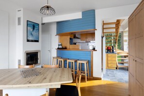 A modern kitchen with a blue accent wall, wooden cabinets, and a built-in stove. - Holiday Home 'Maison Ty Bastian, 100 M²' with Sea View, Private Terrace and Wi-Fi (Saint-Michel-en-Grève)