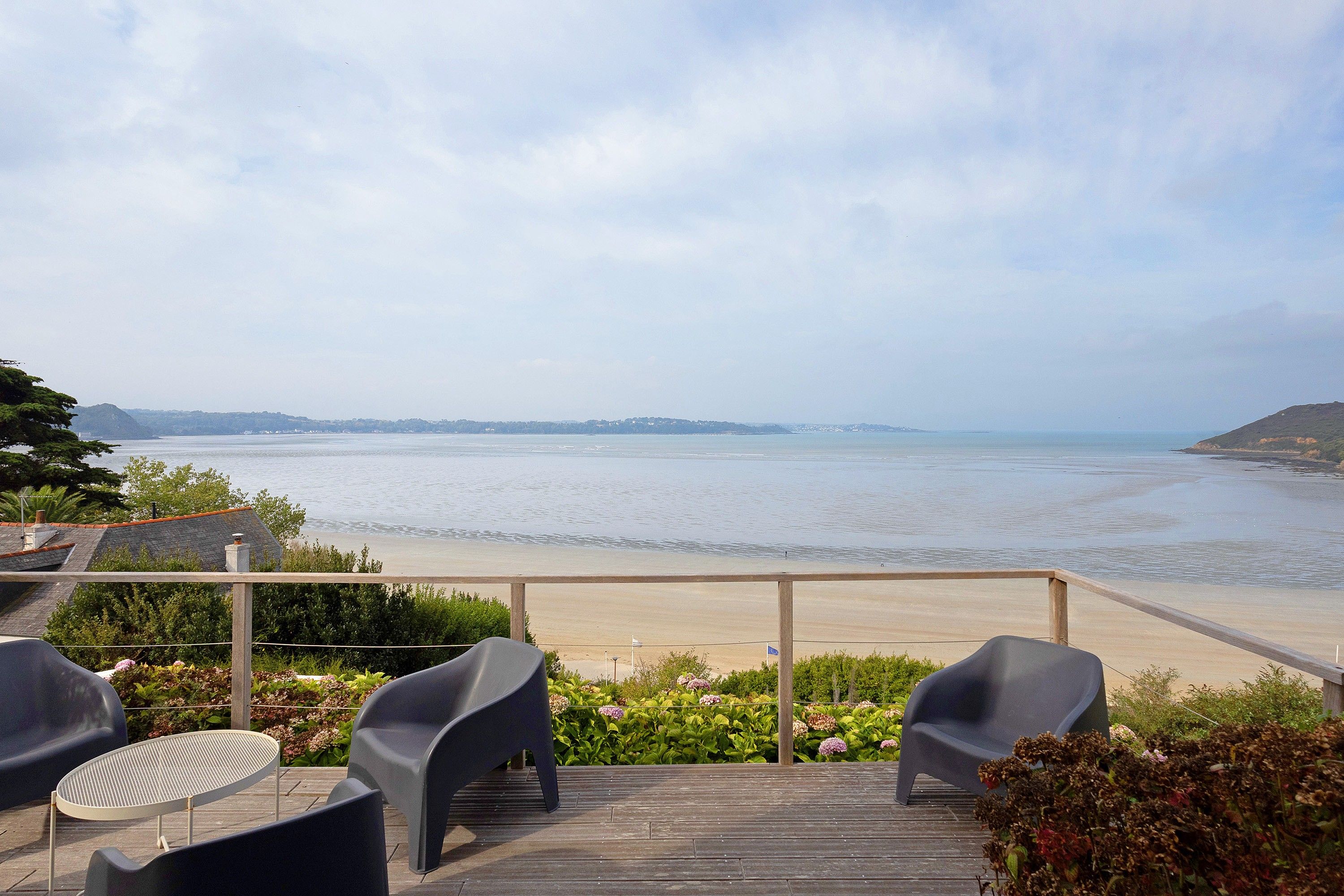 Eine Terrasse mit Stühlen mit Blick auf einen Strand.