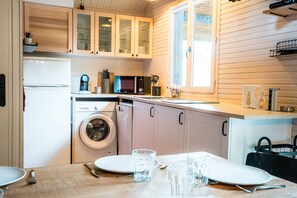 A compact kitchen with a washing machine, microwave, and cabinets.